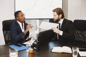 Two business professionals engaged in a planning meeting, discussing documents in a modern office setting. — Allergy Free Vin