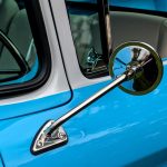 Detailed view of a classic car's chrome side mirror and window trim with vibrant blue paint. — Automotive Industry News Which