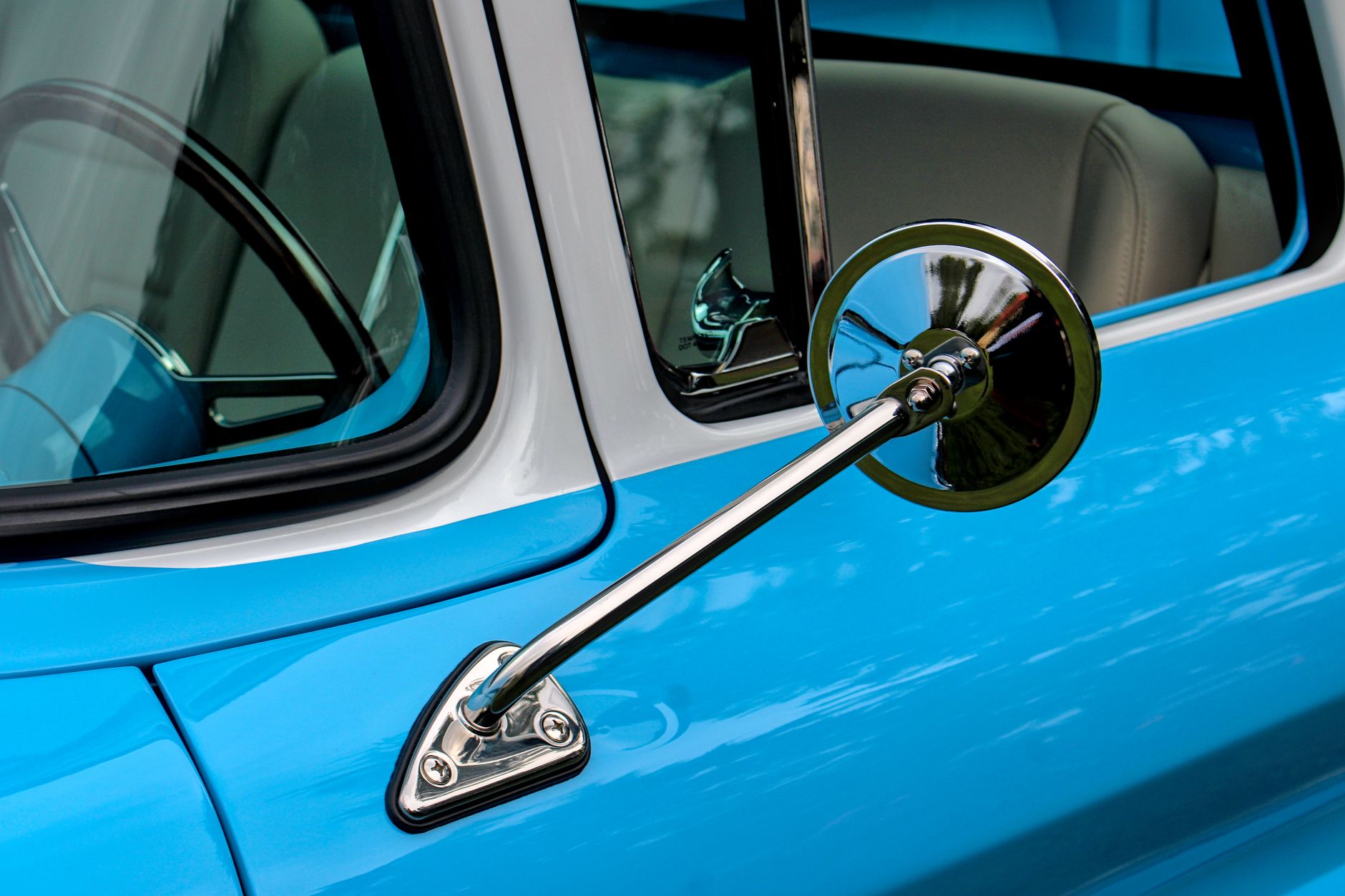 Detailed view of a classic car's chrome side mirror and window trim with vibrant blue paint. — Automotive Industry News Which