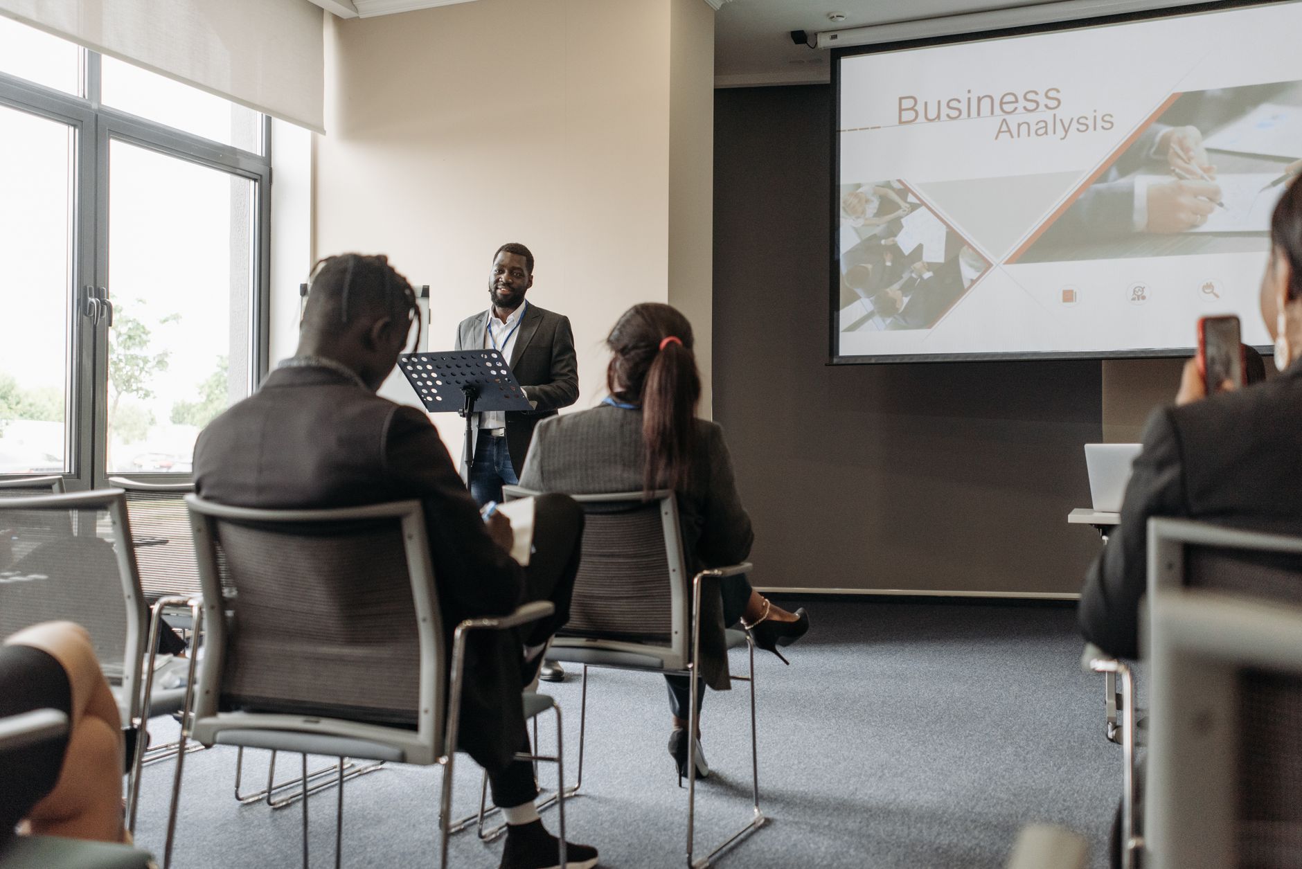 A business professional delivering a presentation in a conference room with diverse attendees. — Bulk Buying: The B2B Feature
