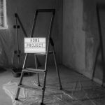 Black and white image of a step ladder with a 'home project' sign in a renovation setting. — Clear Lake Iowa Homes For Sale W