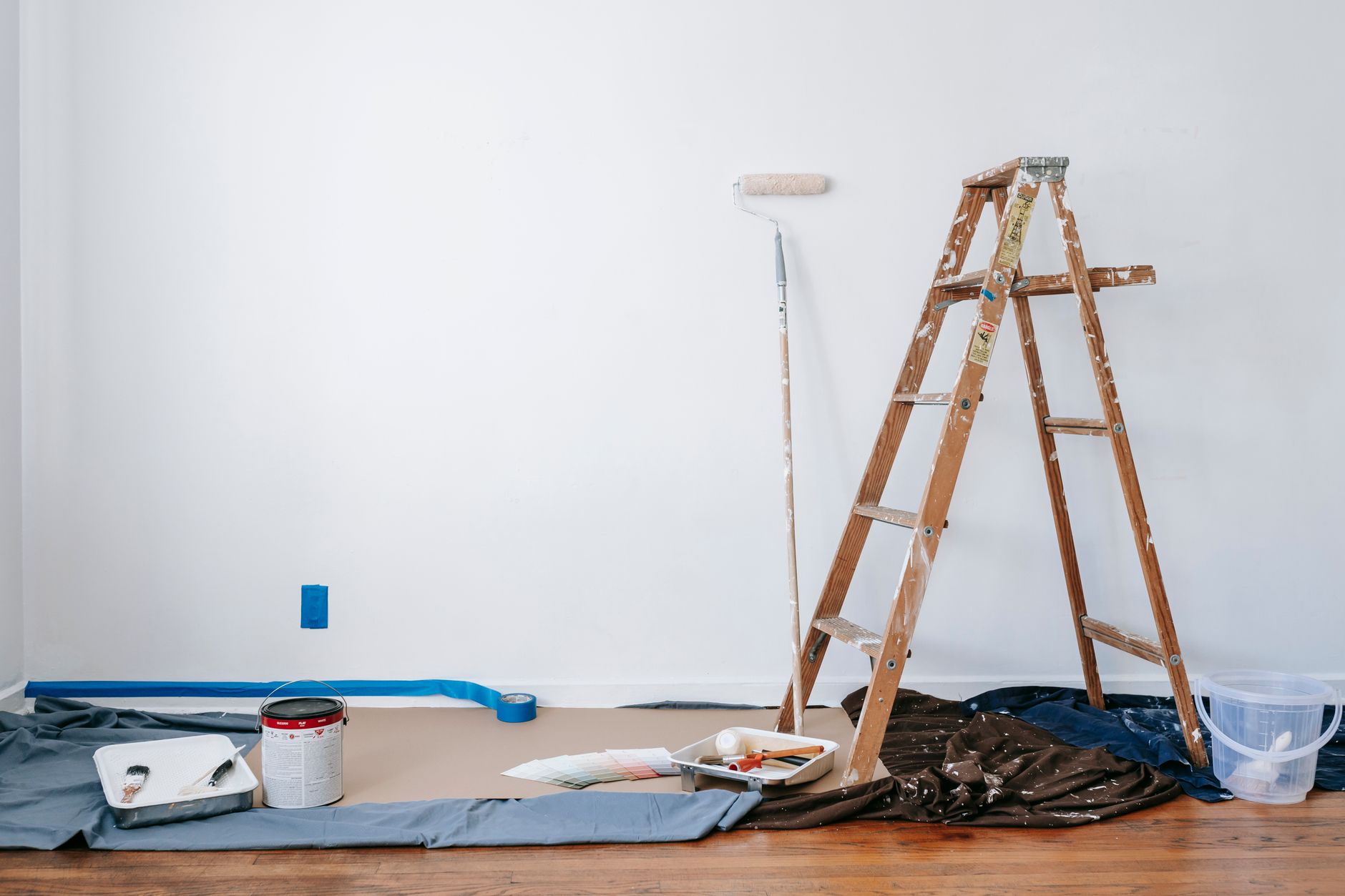 A room prepared for renovation with a ladder, paint supplies, and drop cloth. — Conflict, Discussion and residential Improvem