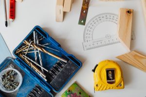 A selection of carpentry tools including drill bits, measuring tape, and protractor in an overhead shot. — Do It Yourself Com