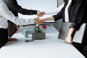 Professionals sealing a deal with a handshake across a conference table during a business meeting. — Easily Exchange Cryptocu