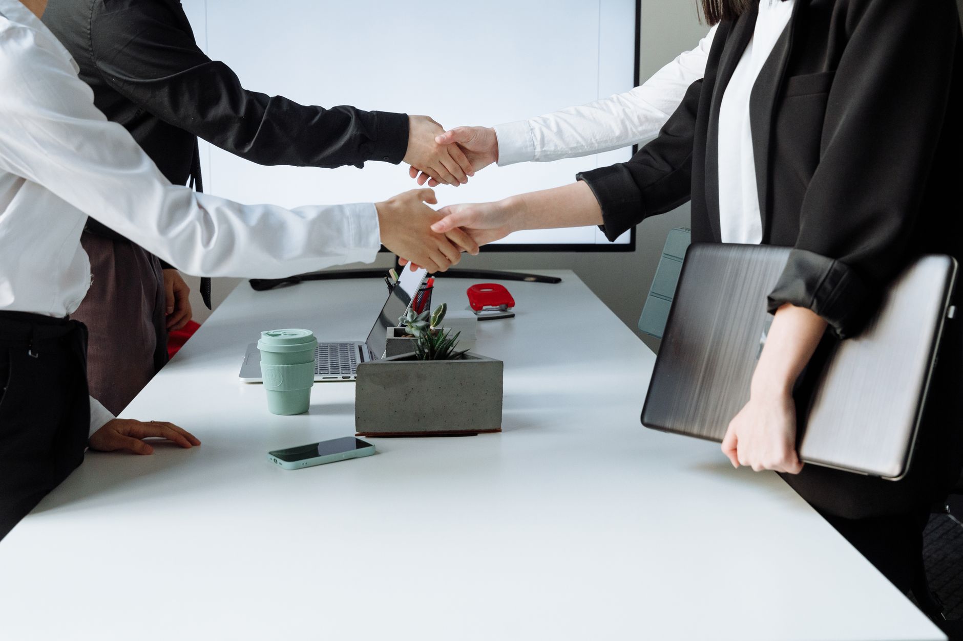 Professionals sealing a deal with a handshake across a conference table during a business meeting. — Easily Exchange Cryptocu