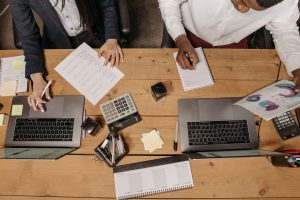 High-angle view of professionals working collaboratively with laptops and documents in an office. — Investing in a GTA 5 Modd