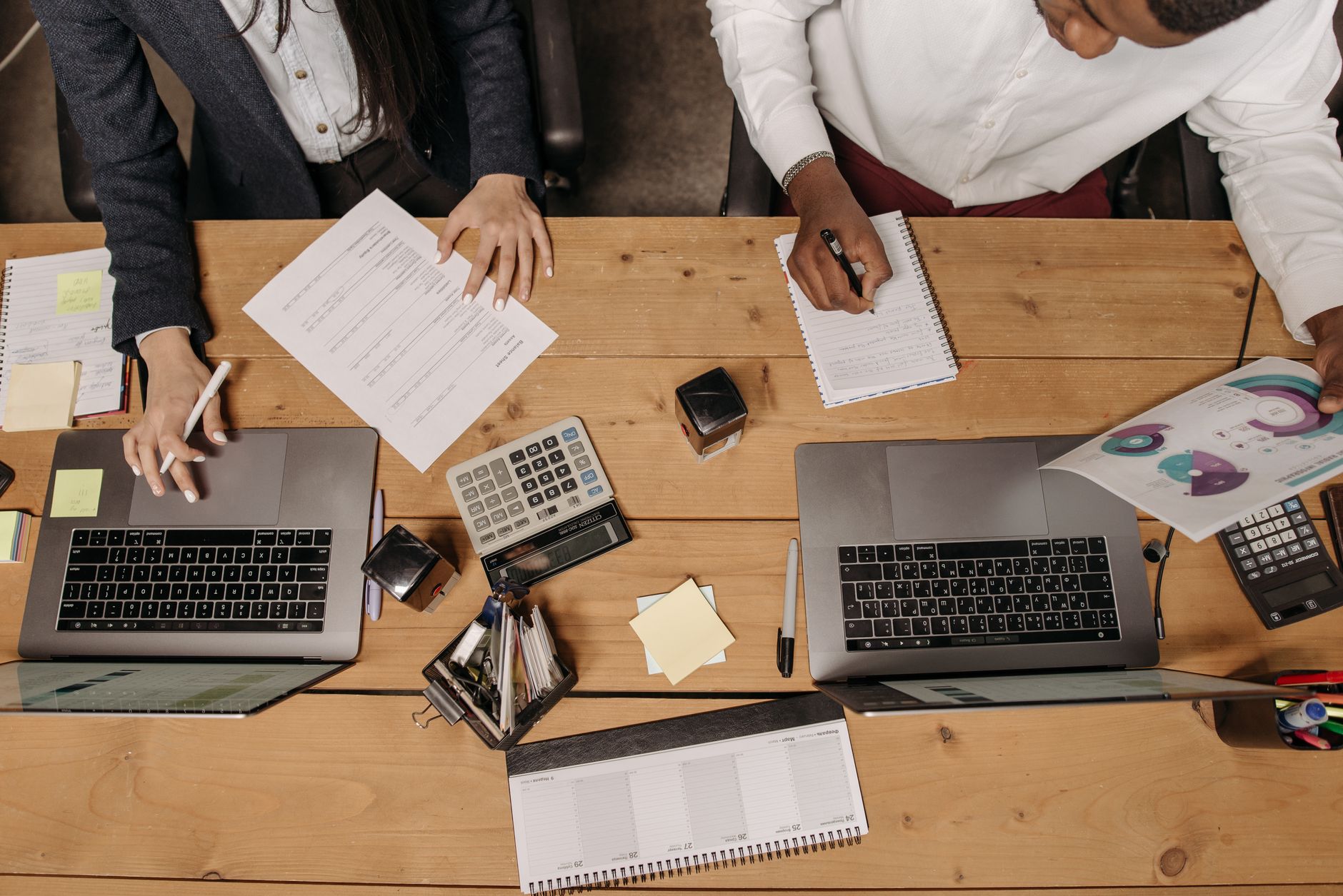 High-angle view of professionals working collaboratively with laptops and documents in an office. — Investing in a GTA 5 Modd