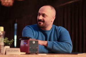 Casual portrait of a man in a blue sweater sitting indoors at a restaurant. — Know About The BEST WEED DELIVERY SURREY