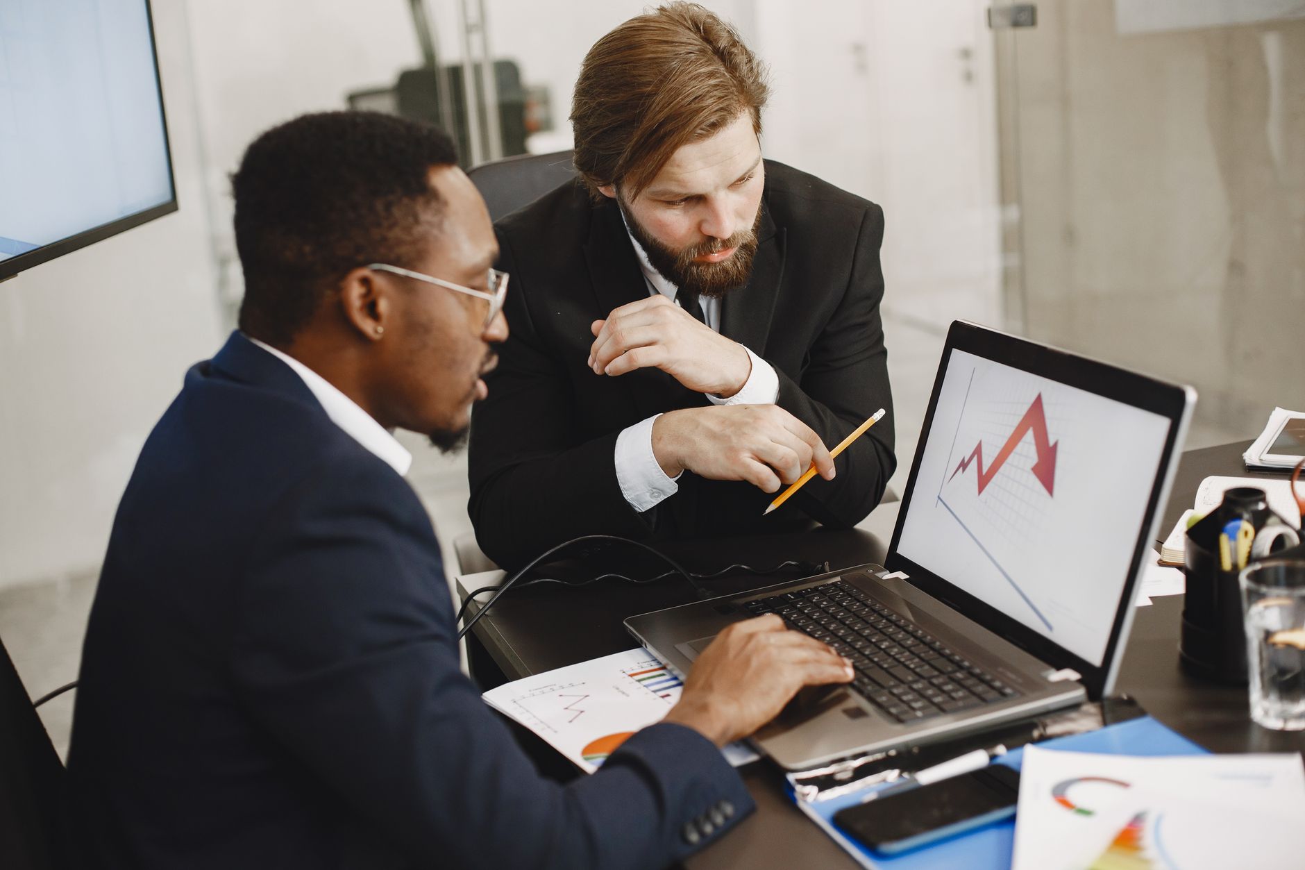 Two business professionals discuss marketing data on a laptop in a modern office. — Low-Cost Chiropractic Therapy for Every B