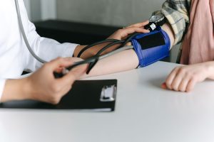 A healthcare worker uses a sphygmomanometer to check a patient's blood pressure in a medical office. — Medicare Supplement In