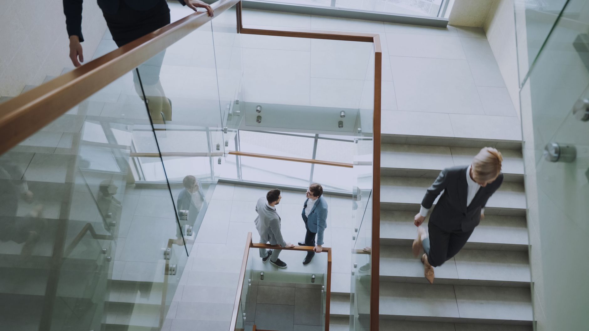 Aerial view of professionals conversing in a glass staircase in a modern office. — Minimizing Risk with Apex Trader Investmen