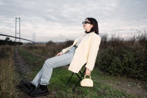 A stylish woman in sunglasses relaxes on a chair by a bridge in nature. — Navigating Chronic Pain: When and How to Consult a