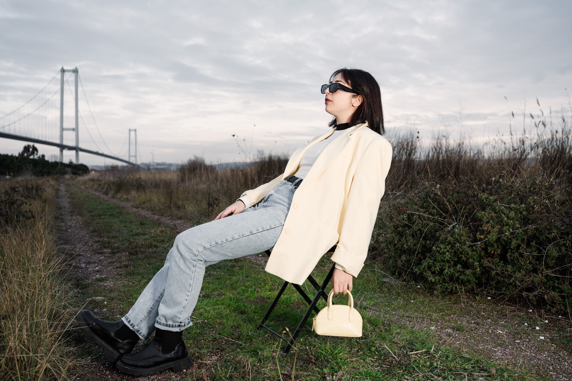 A stylish woman in sunglasses relaxes on a chair by a bridge in nature. — Navigating Chronic Pain: When and How to Consult a