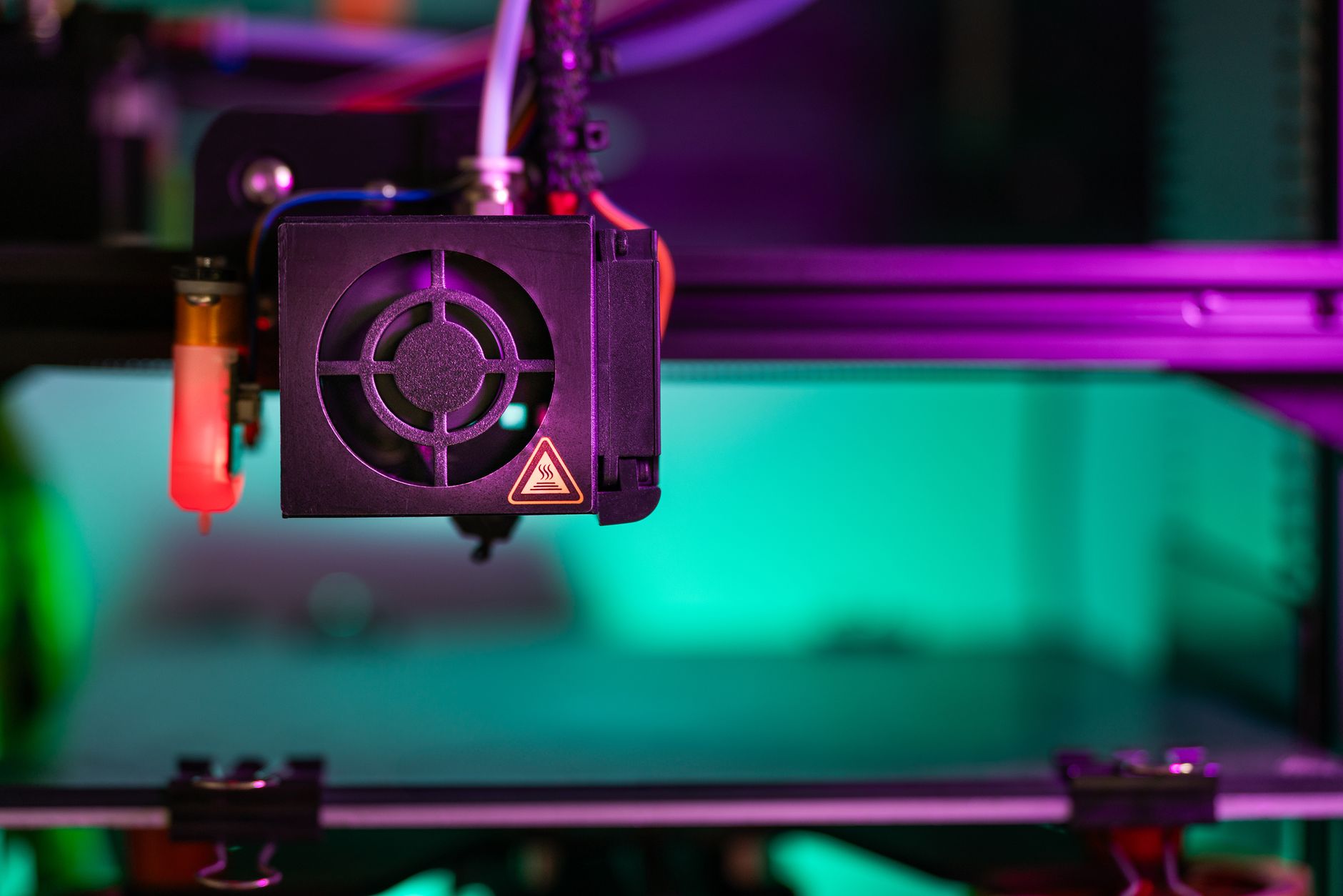 Vibrant close-up of a 3D printer component in action with colorful lighting creating a modern industrial vibe. — Online Small
