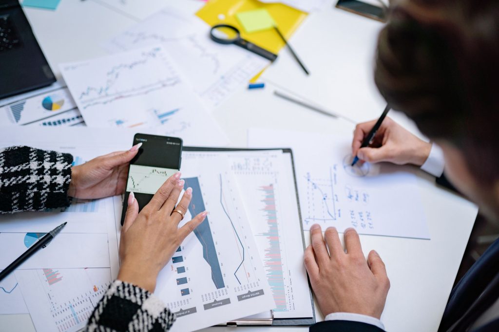 Overhead view of people analyzing financial graphs and data with smartphone and documents. — Stress-Free Loans & Expert Guida