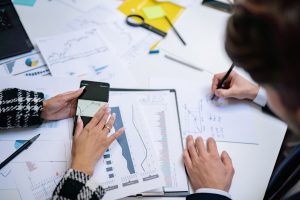 Overhead view of people analyzing financial graphs and data with smartphone and documents. — Stress-Free Loans & Expert Guida