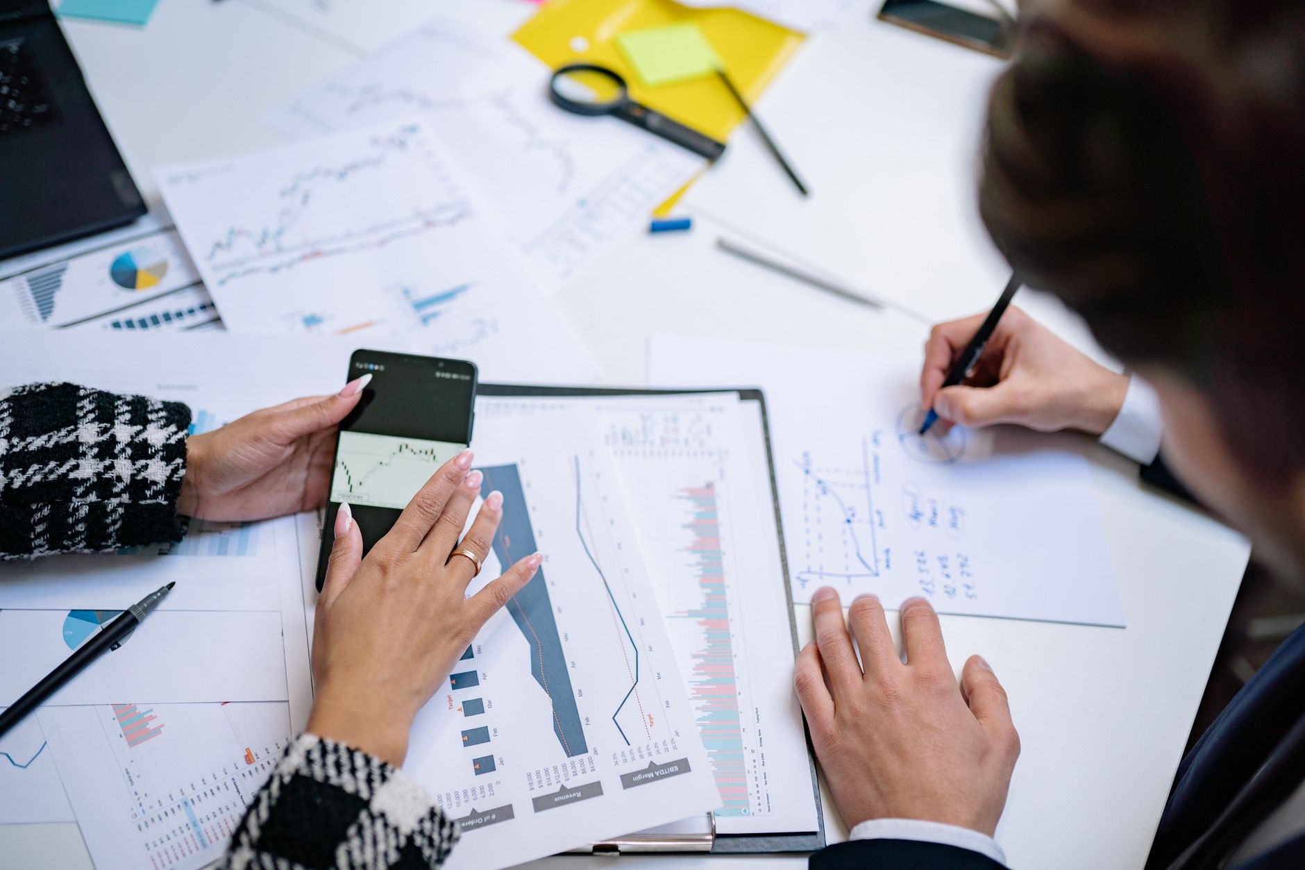 Overhead view of people analyzing financial graphs and data with smartphone and documents. — Stress-Free Loans & Expert Guida