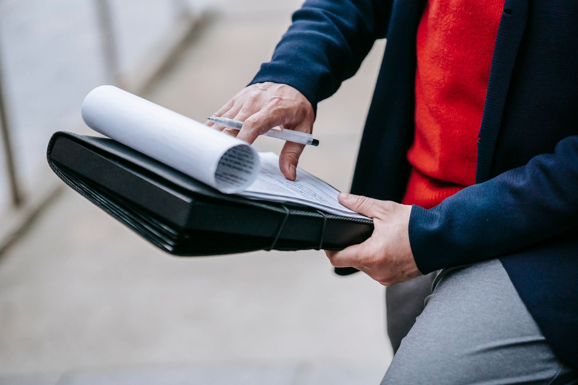 Close-up of a professional person reviewing documents outdoors. Engaged in work with focus on writing materials. — Stuart Pil