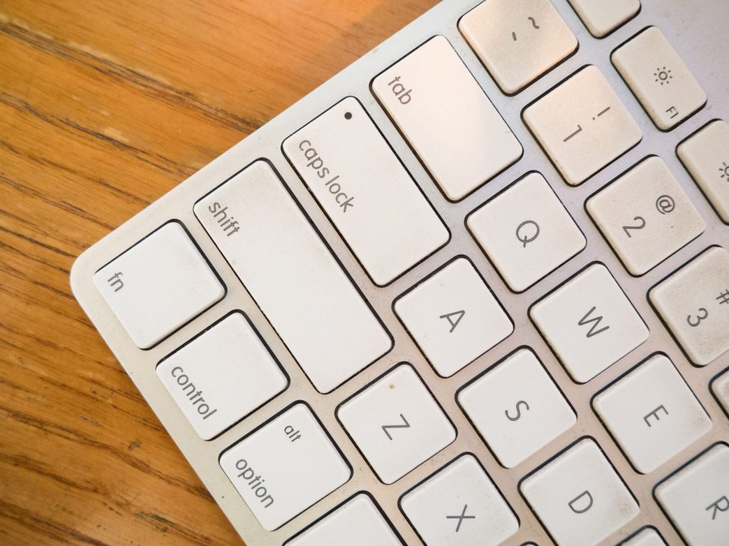 A detailed close-up of a modern computer keyboard on a wooden desk. — Technology - An Ever Increasing Fad