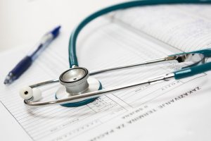 A stethoscope and pen resting on a medical report in a healthcare setting. — Ten Items to Ask Your Wellbeing Insurance Provid