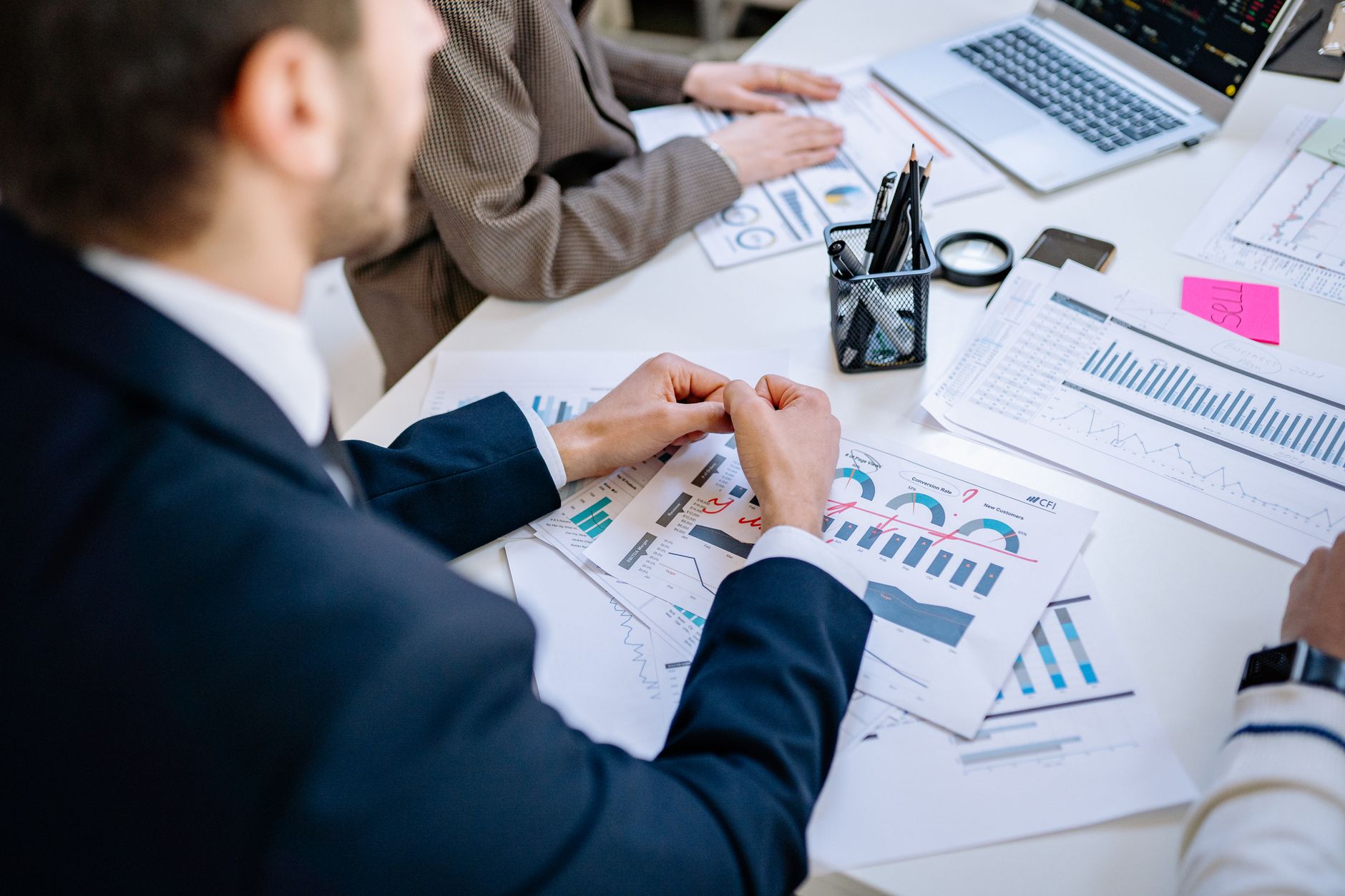 Business team analyzing financial graphs at a meeting table, fostering collaboration in an office environment. — The Body Sho