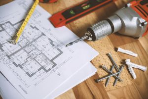 Close-up of construction blueprint with tools like drill and screws on a wooden table. — The Number Of Do It Yourself Grants