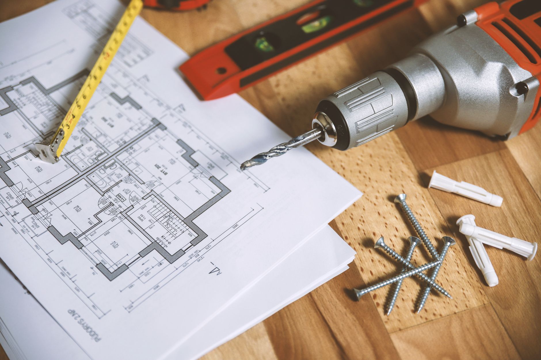 Close-up of construction blueprint with tools like drill and screws on a wooden table. — The Number Of Do It Yourself Grants