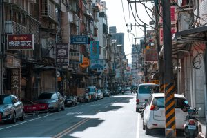 A busy street lined with cars and various colorful business signs on a sunny day. — The Role of Nifty Futures in Stock market