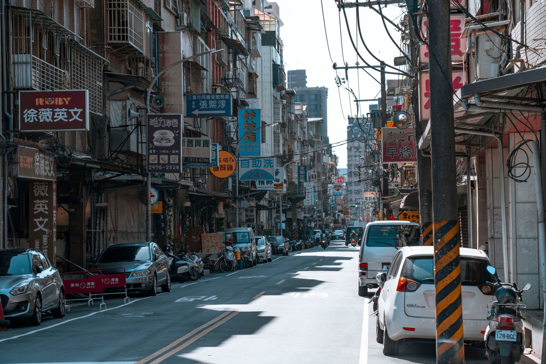 A busy street lined with cars and various colorful business signs on a sunny day. — The Role of Nifty Futures in Stock market