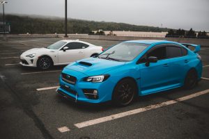 Modern fast clean automobiles parked on concrete surface with stripes on gloomy cloudy day — What Let's Focus On Automotive S