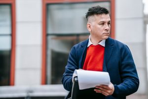 A serious man holding papers, dressed professionally in an urban environment. — Why You Need To Brand Yourself